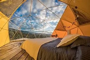 Inside a glamping dome with a bed and mountain view